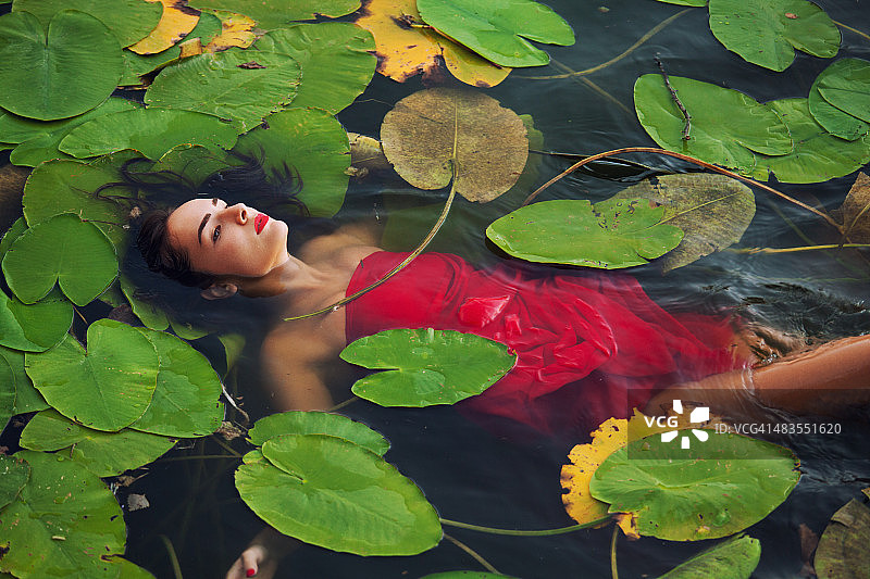 年轻女人漂浮在沼泽的水面上图片素材