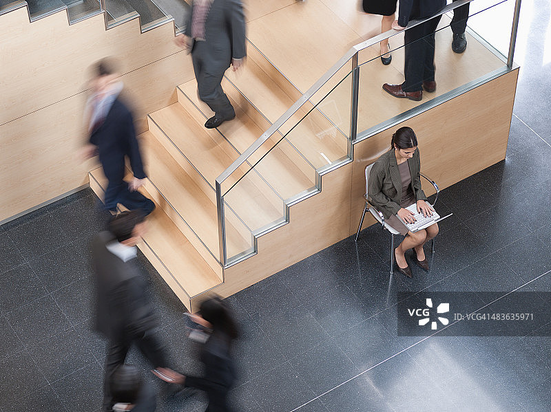 在繁忙的办公室走廊工作的女商人图片素材