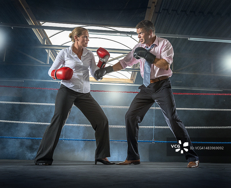 商务情侣在烟雾缭绕的拳击场上争吵图片素材