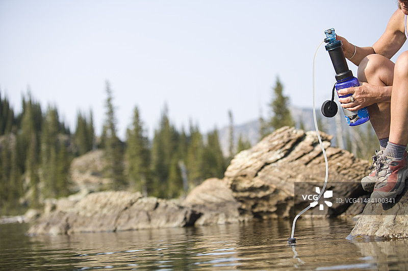 在背包旅行时过滤湖水的女人图片素材