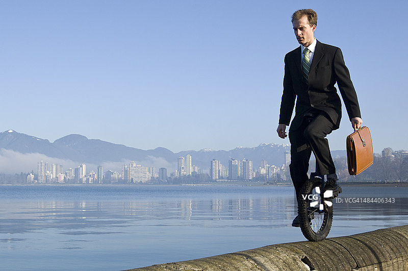 穿着西装的男人在城市背景下骑独轮车图片素材