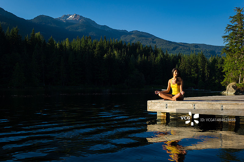 日出时分，宁静湖畔的简易冥想姿势图片素材