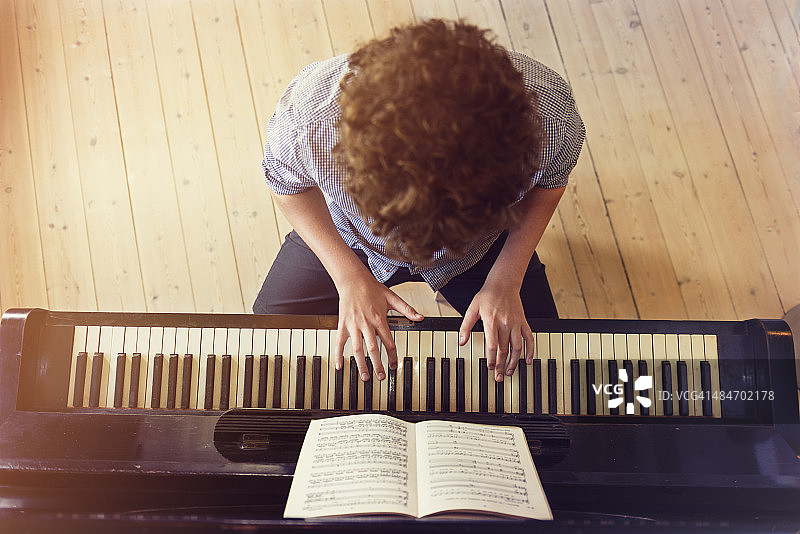 阳光房里弹钢琴的少年俯视图图片素材