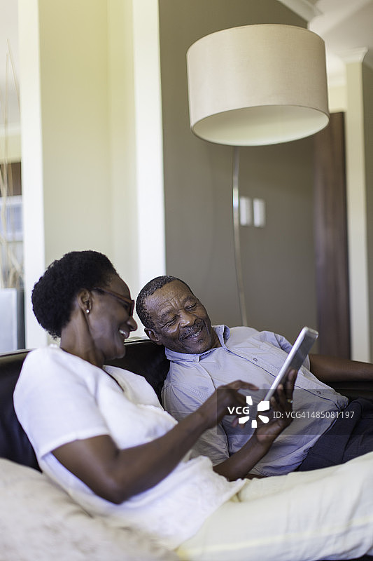 正在欢笑并一起使用数位平板电脑的非洲老年夫妇图片素材