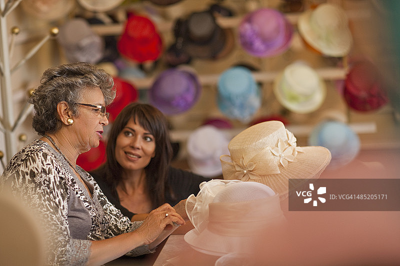 女帽匠在商店为顾客装饰帽子图片素材