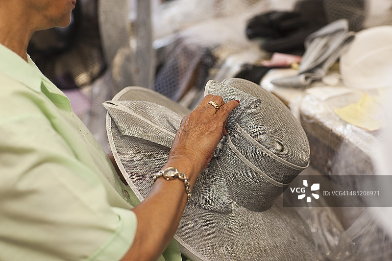在传统制帽店拿着帽子的老年妇女图片素材