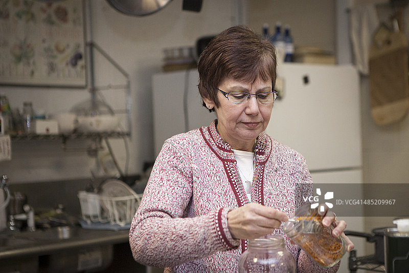 健康食品店主将草药放入罐中图片素材