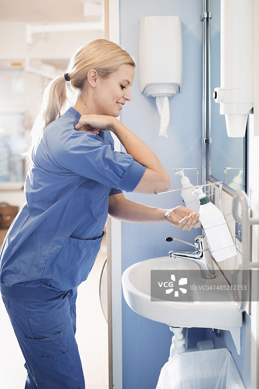 在浴室用皂液器洗手的年轻护士侧视图图片素材