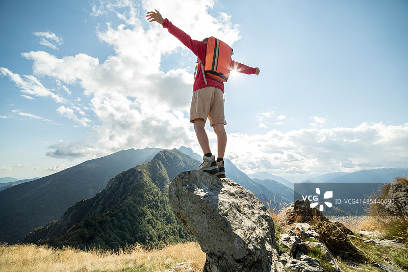 徒步男子站在山顶张开双臂拥抱自由图片素材