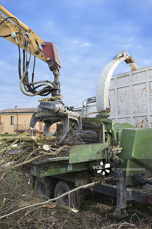起重机将树枝放入碎木机中图片素材