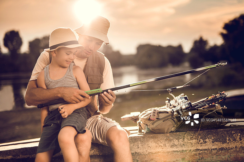 日落时分，父亲和小儿子一起检查钓鱼竿图片素材