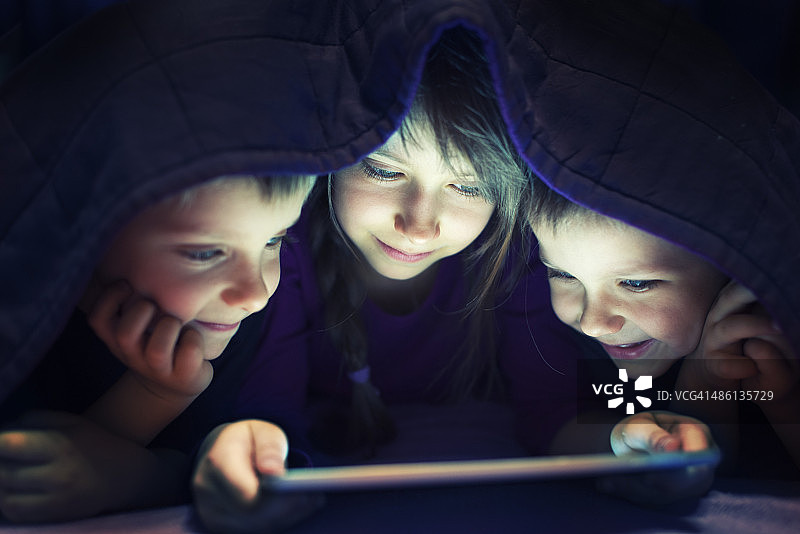 孩子们偷偷地在平板电脑上看书图片素材