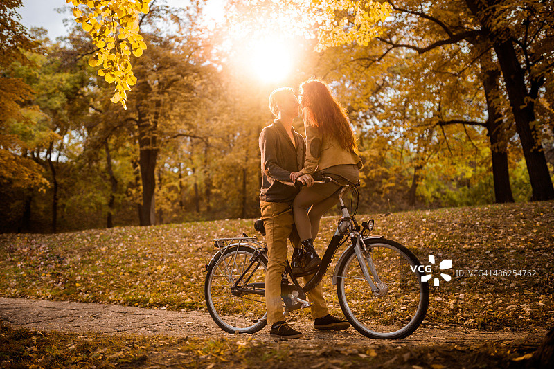 年轻女子亲吻骑自行车的男友图片素材