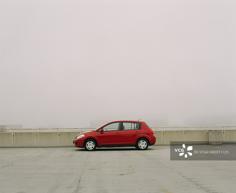 雾中停车库顶部的红色小型汽车图片素材