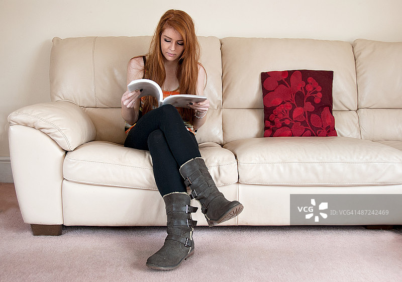 在现代奶油色沙发上阅读的少女图片素材