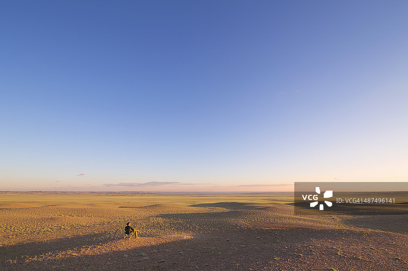 男人坐在广阔的平原上，内蒙古图片素材