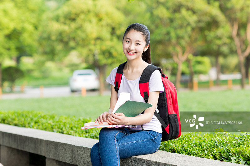 背着背包和笔记本的亚洲女学生微笑图片素材