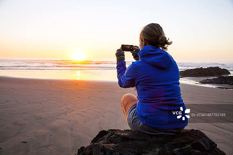 在海滩上拍摄日出的白人女性图片素材
