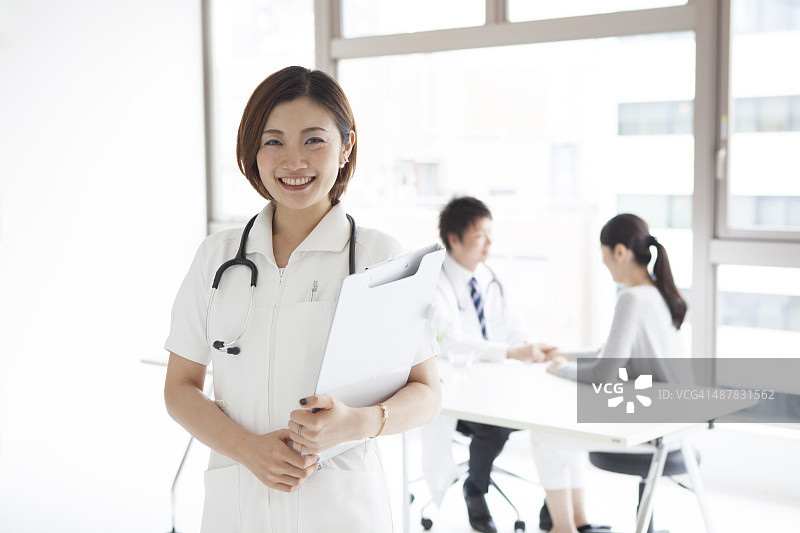 在医疗团队前微笑的护士肖像图片素材