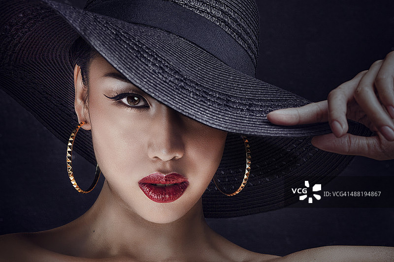 戴着黑色大帽子的神秘亚洲女人图片素材