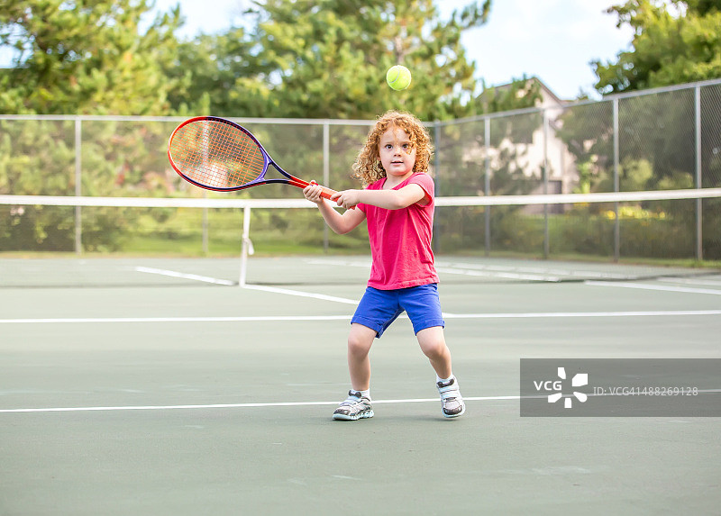 打网球的卷发年轻女孩图片素材