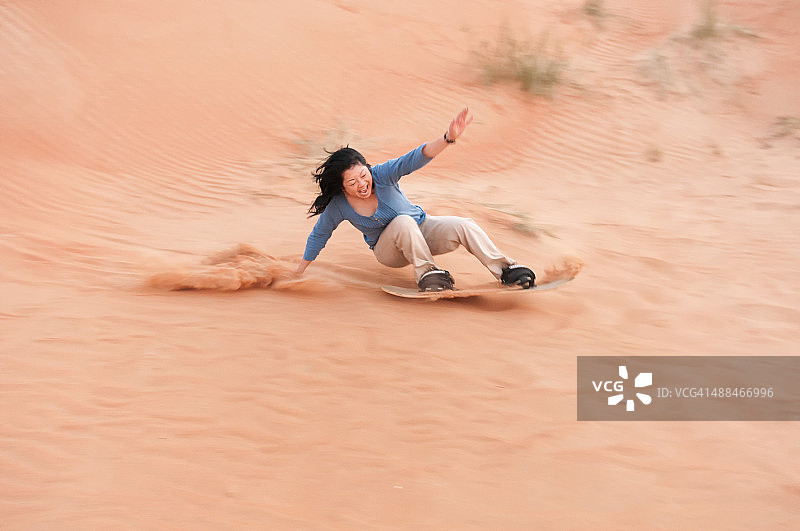 在迪拜沙迦沙漠体验滑沙的刺激女性游客图片素材