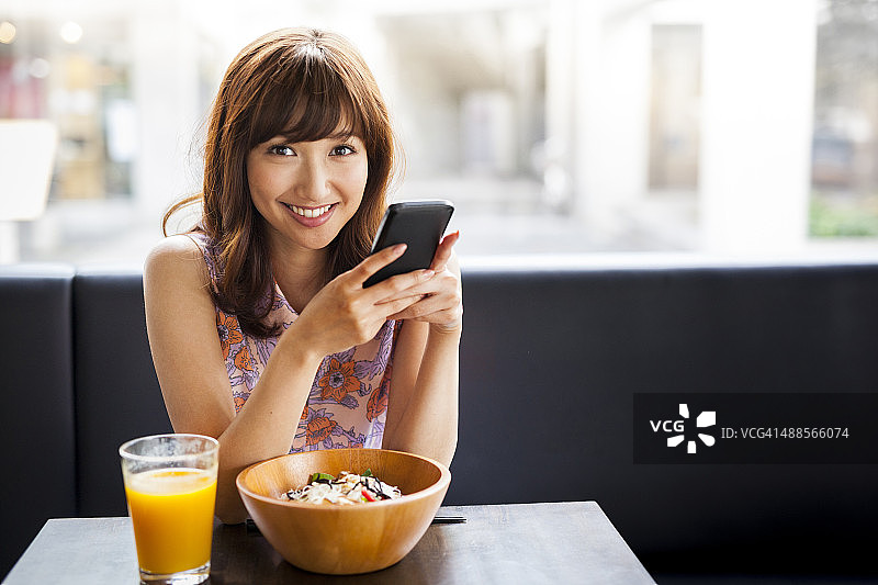 用智能手机吃午餐的迷人女孩图片素材