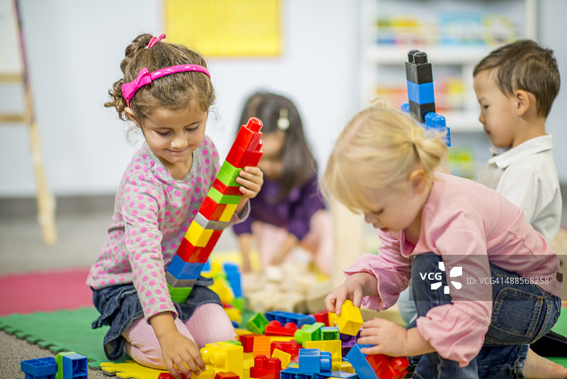 女孩搭建高高的塑料积木塔图片素材