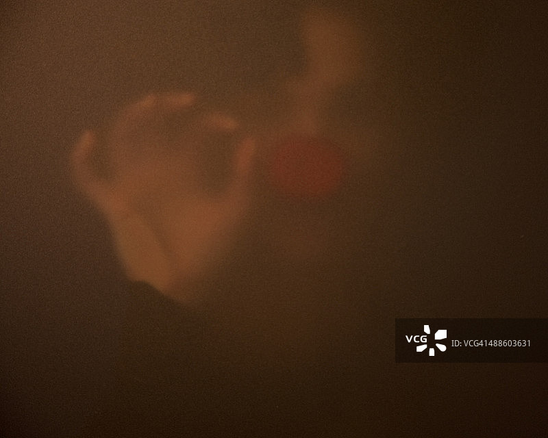 隔着不透明窗户，戴着小丑鼻子的女孩图片素材