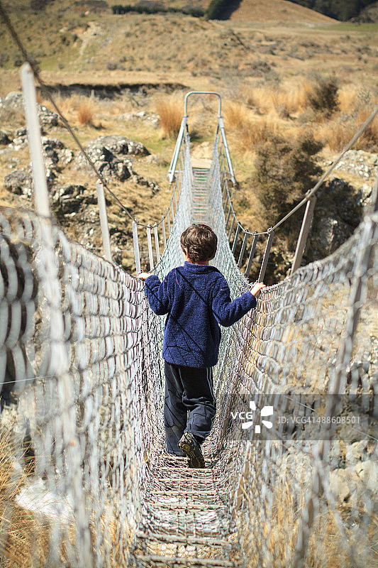 男孩在绳索桥上过河图片素材