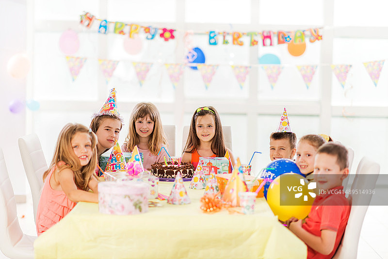 坐在生日派对上看着镜头的微笑儿童图片素材