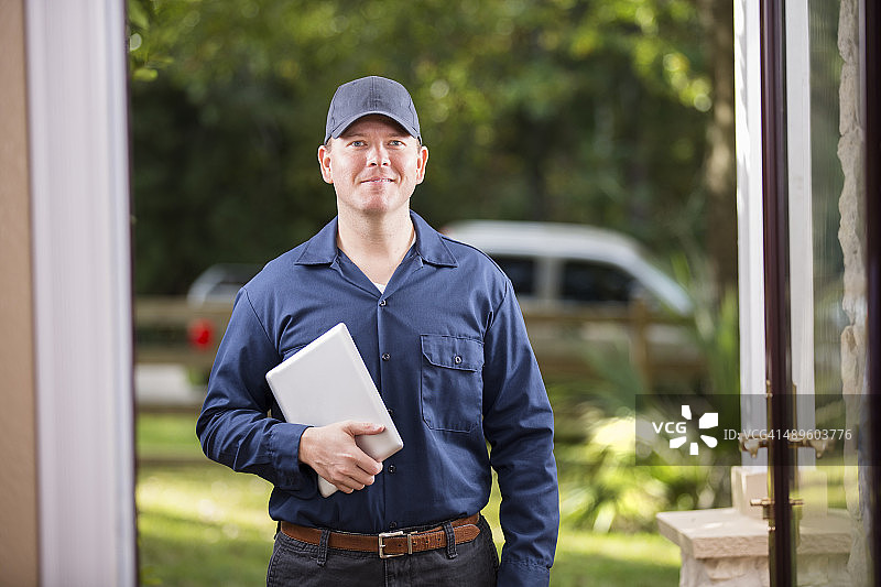 服务行业：维修人员在顾客前门使用数字平板电脑。图片素材