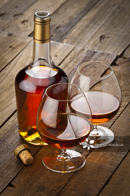 酒杯和干邑白兰地酒瓶在乡村木桌上图片素材