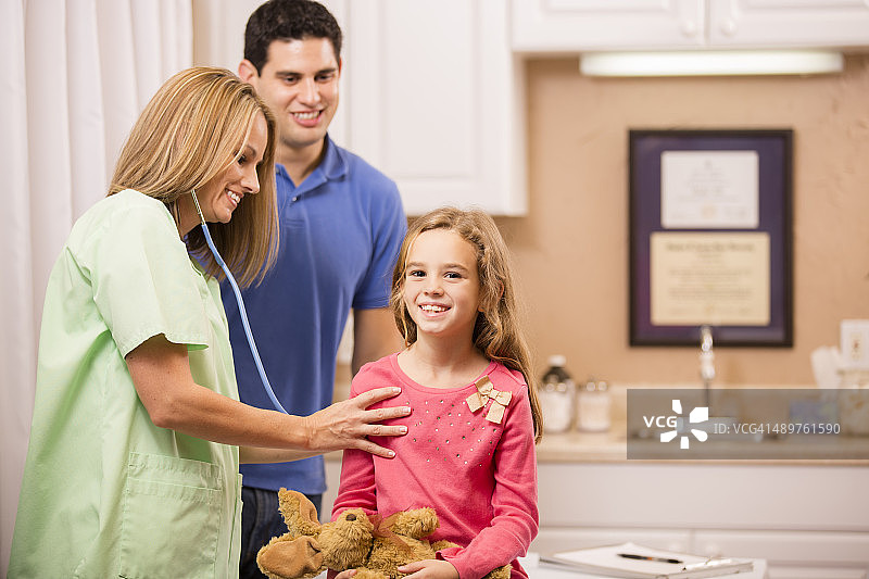 小女孩在儿科医生办公室与儿科医生和父亲在一起图片素材