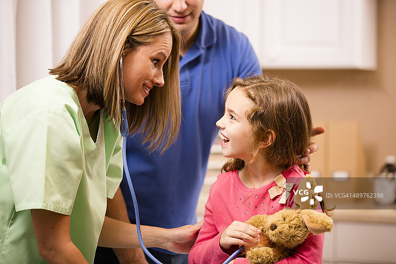 小女孩在儿科医生办公室与儿科医生和父亲在一起图片素材