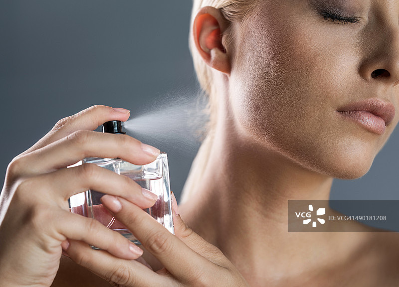 女人往脖子上喷香水的特写镜头图片素材