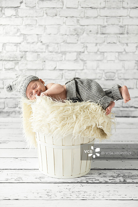 一个月大的男婴躺在白色篮子里，室内图片素材
