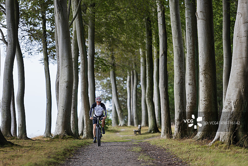 年长的男人在森林小路上骑山地自行车图片素材