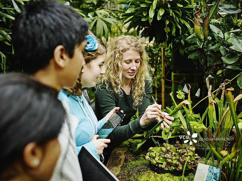女植物学家与年轻学生在温室里图片素材