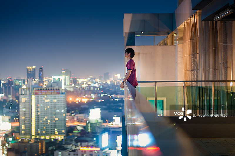 男士们站在摩天大楼的屋顶上俯瞰城市景观图片素材