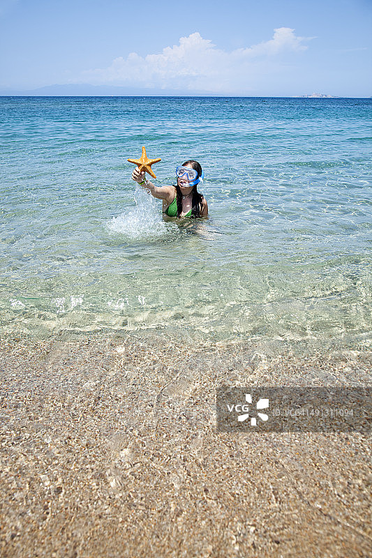 在海滩上展示海星的女孩图片素材