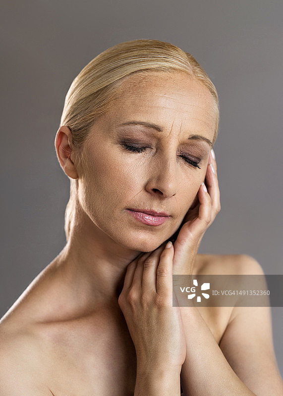 灰色背景下触摸皮肤的中年妇女 портрет图片素材
