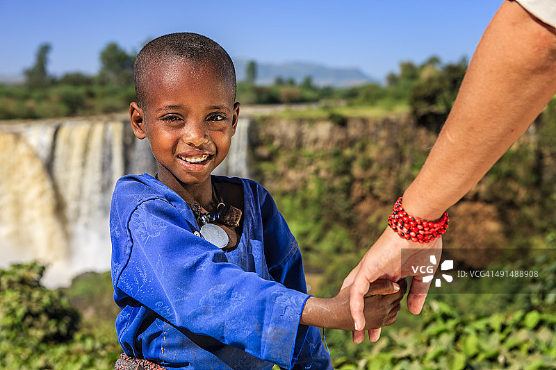 白人女性牵着非洲儿童的手图片素材