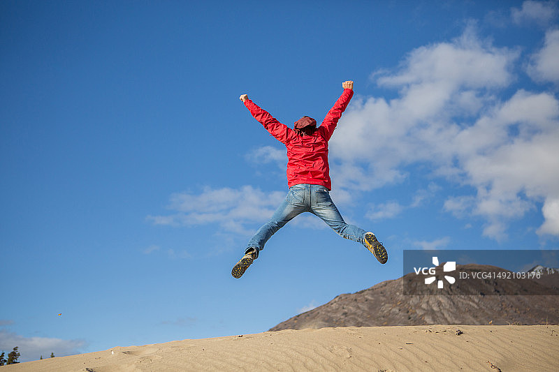 快乐的年轻男子在沙漠中跳跃图片素材