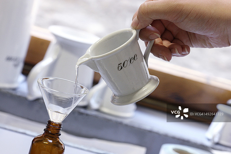 药剂师通过漏斗将药液倒入药瓶图片素材