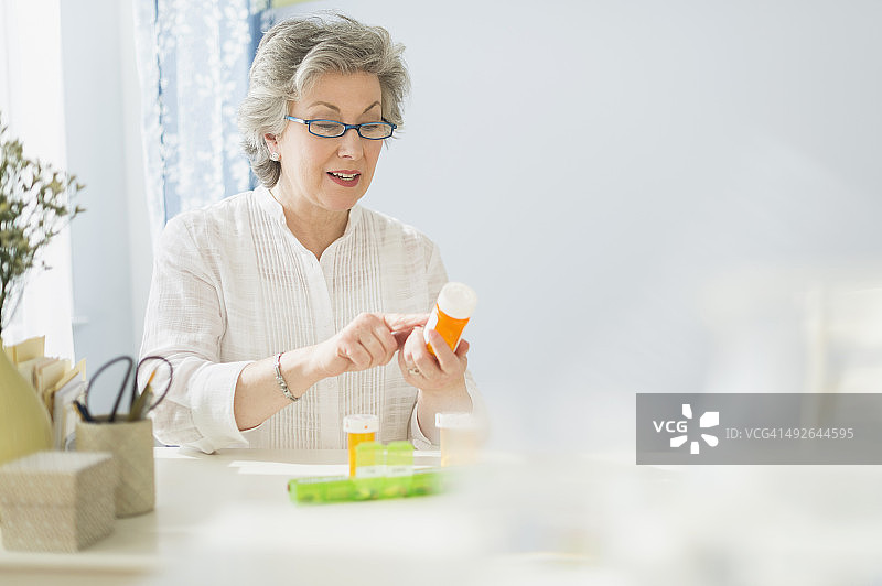 中年妇女在美国新泽西州泽西市阅读药瓶上的标签图片素材