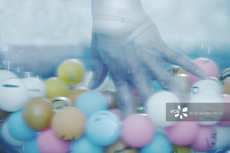 手从玻璃碗中抽取彩票球特写图片素材