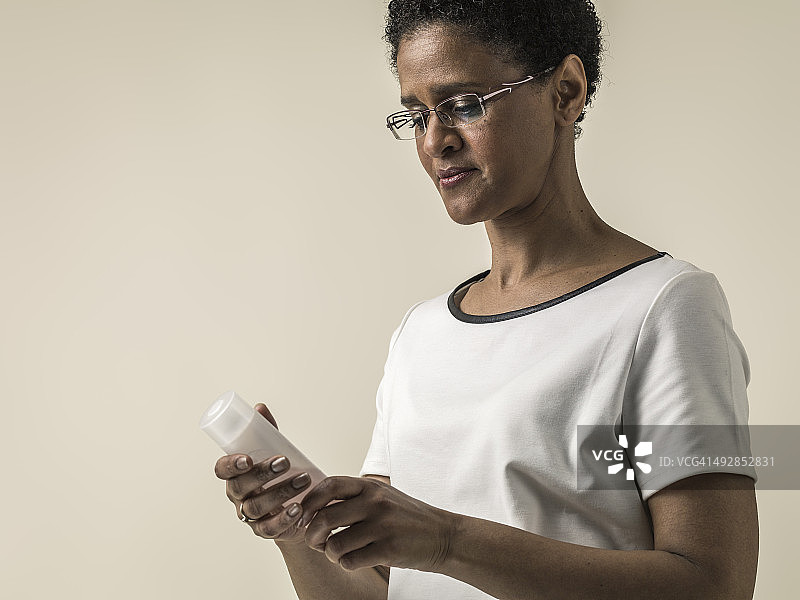 黑人女人阅读瓶子上的说明图片素材