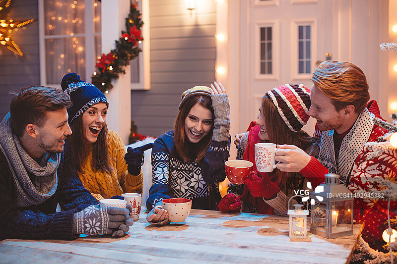 朋友们坐在房子前的户外桌旁图片素材