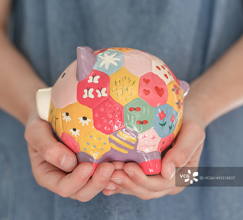 手拿彩色小猪储蓄罐图片素材